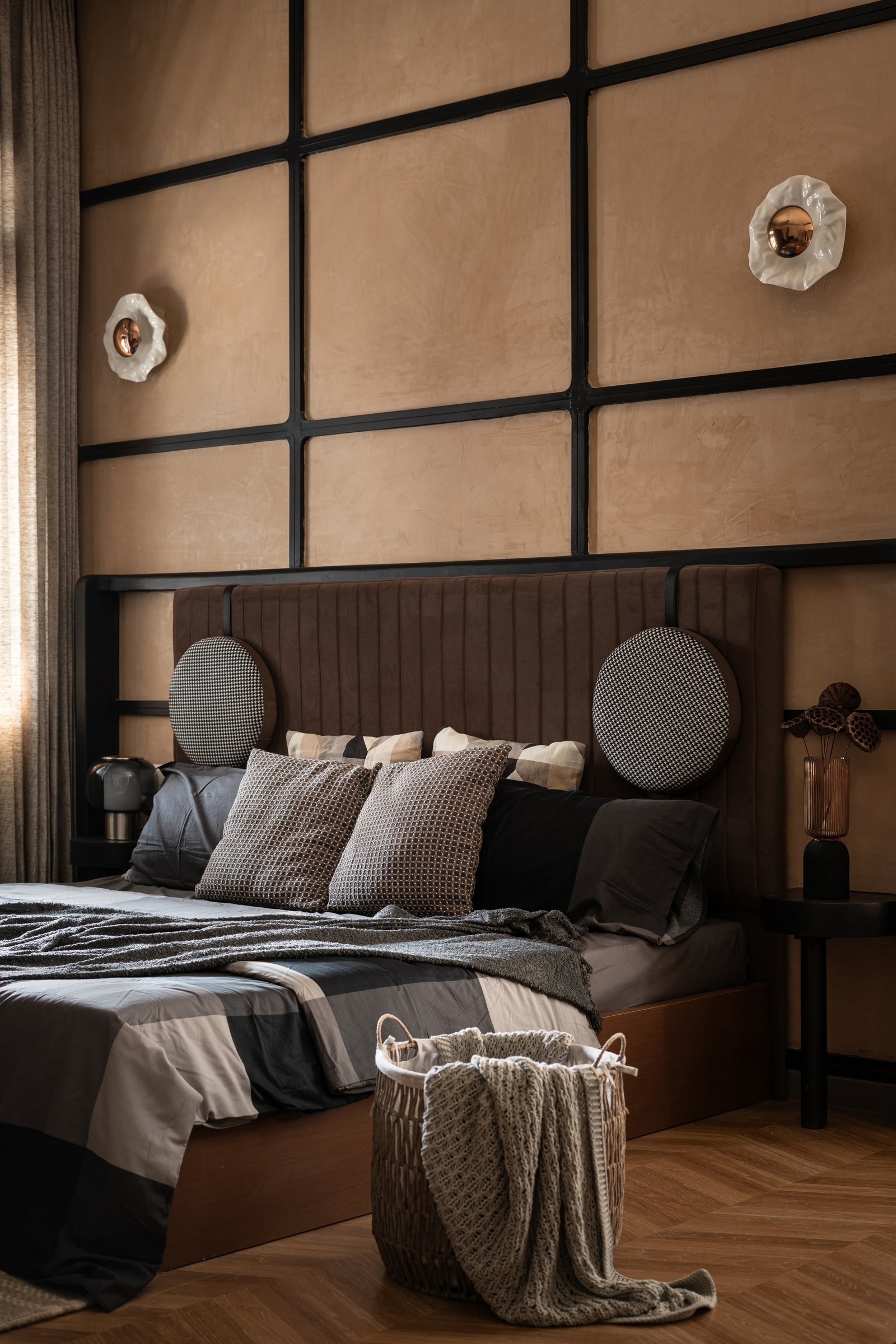 The primary bedroom, with leather-finished panels framed in blackened steel behind a channel-tufted velvet headboard