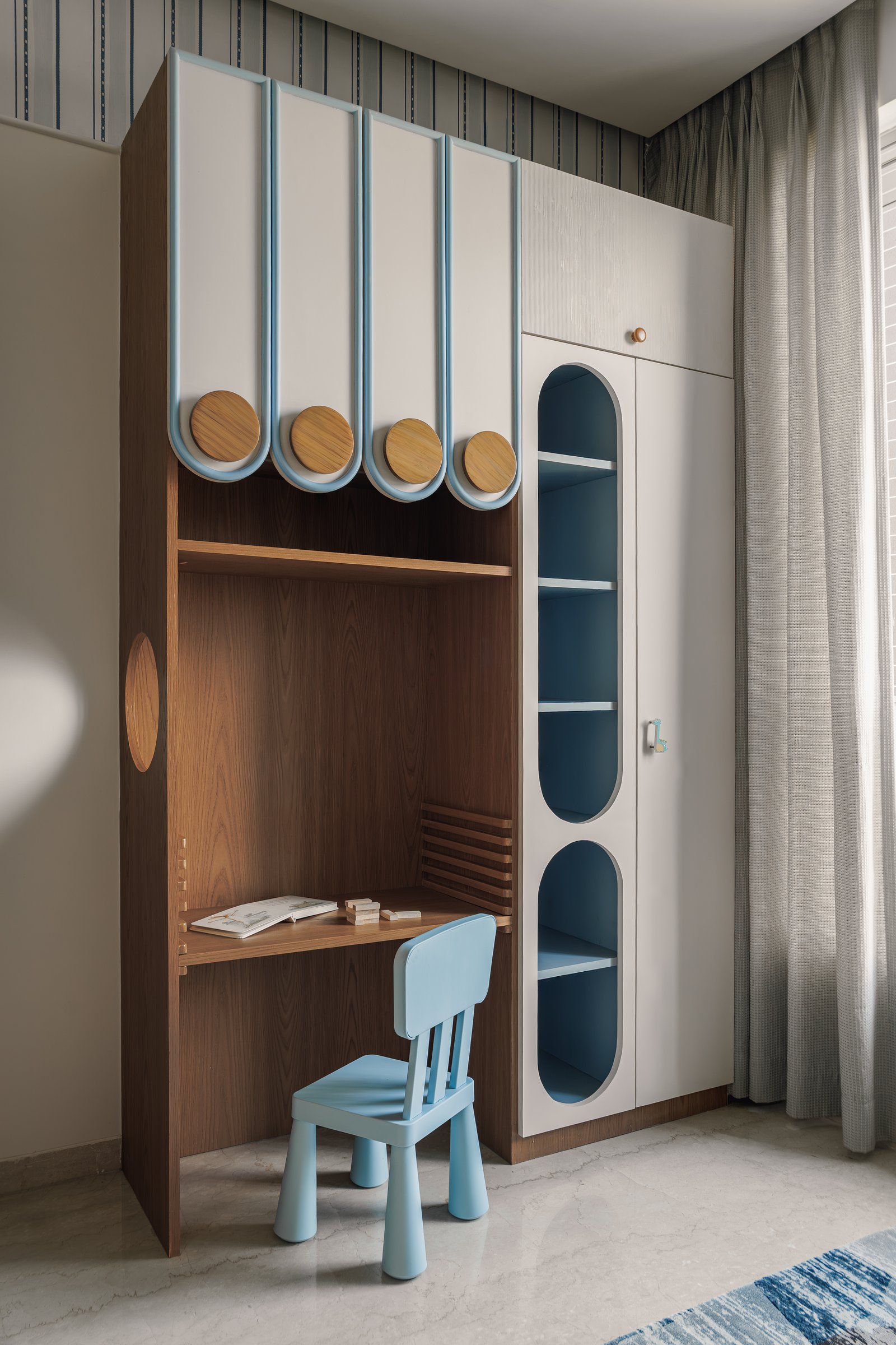 The study niche, a compact composition of warm wood joinery and rounded storage shutters