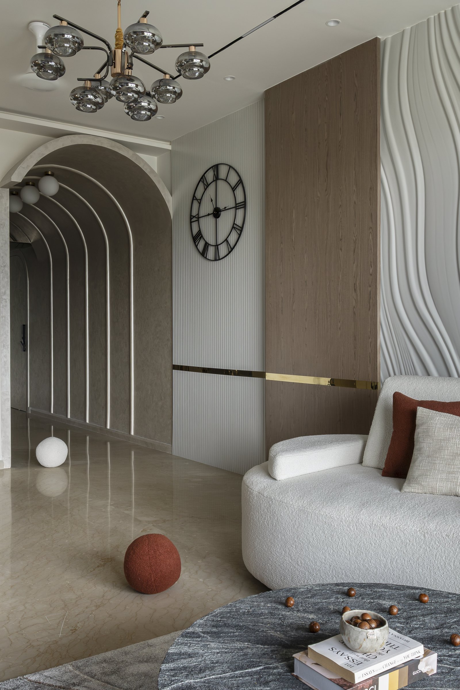 The vaulted arched passage threading into the living room, its concentric reveals echoed in the curved seating and circular tables
