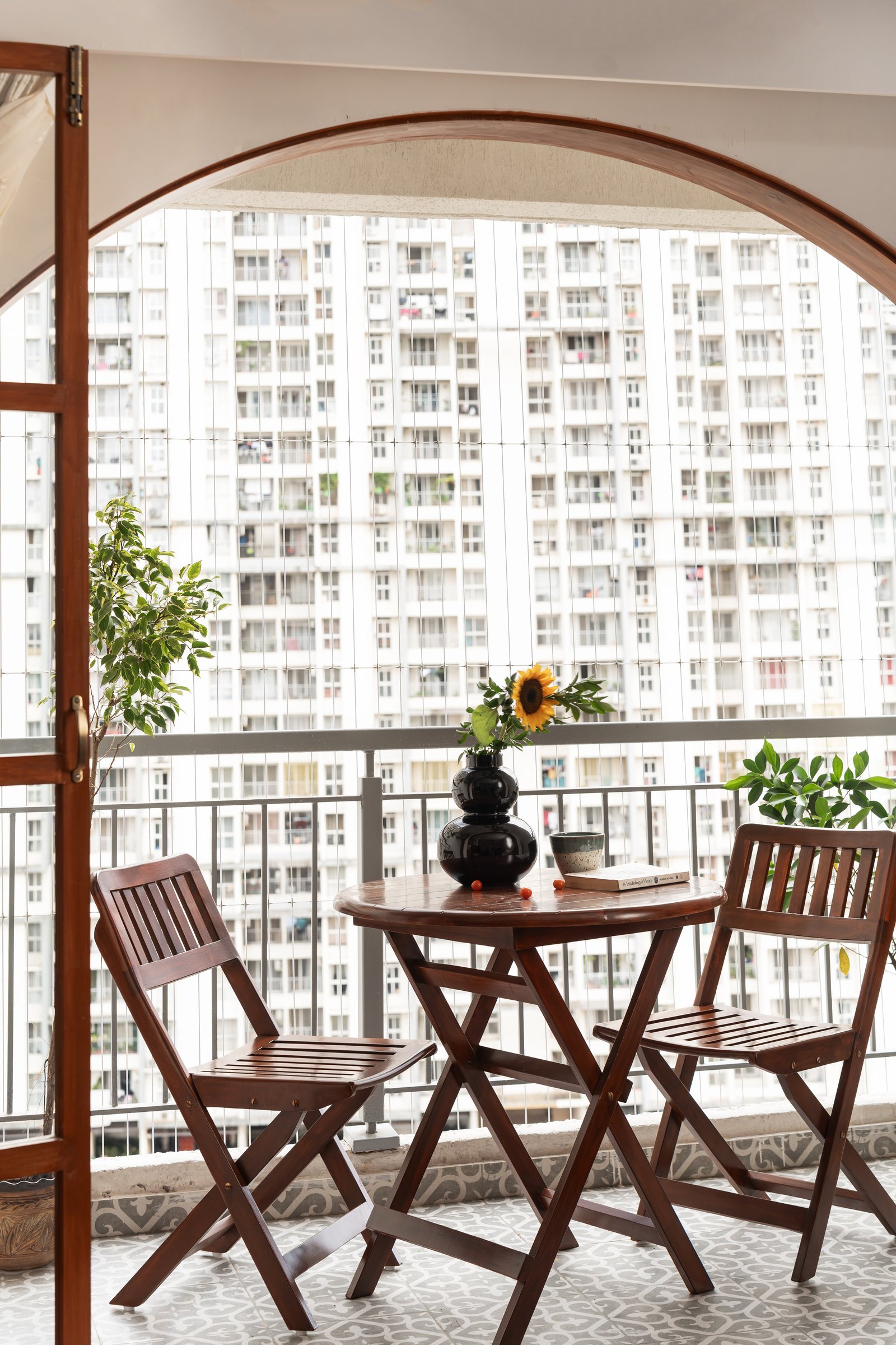 The balcony, where a wooden bistro set sits against patterned cement tiles beneath an arched doorway