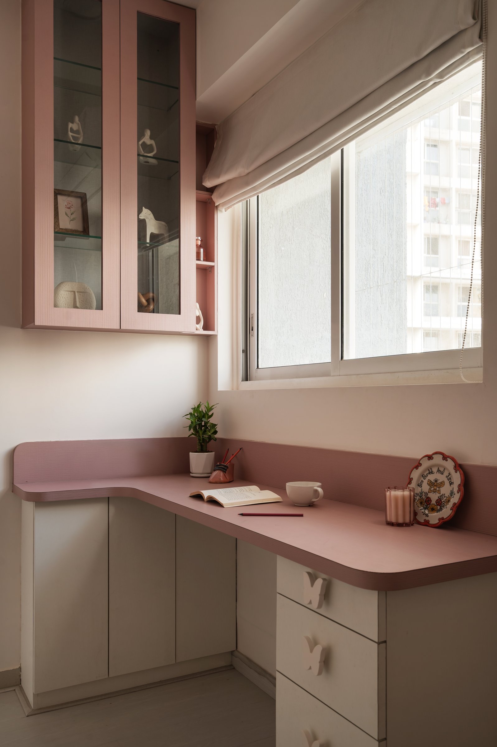 A built-in study desk occupies the window corner, its arched display cabinet continuing the room's language