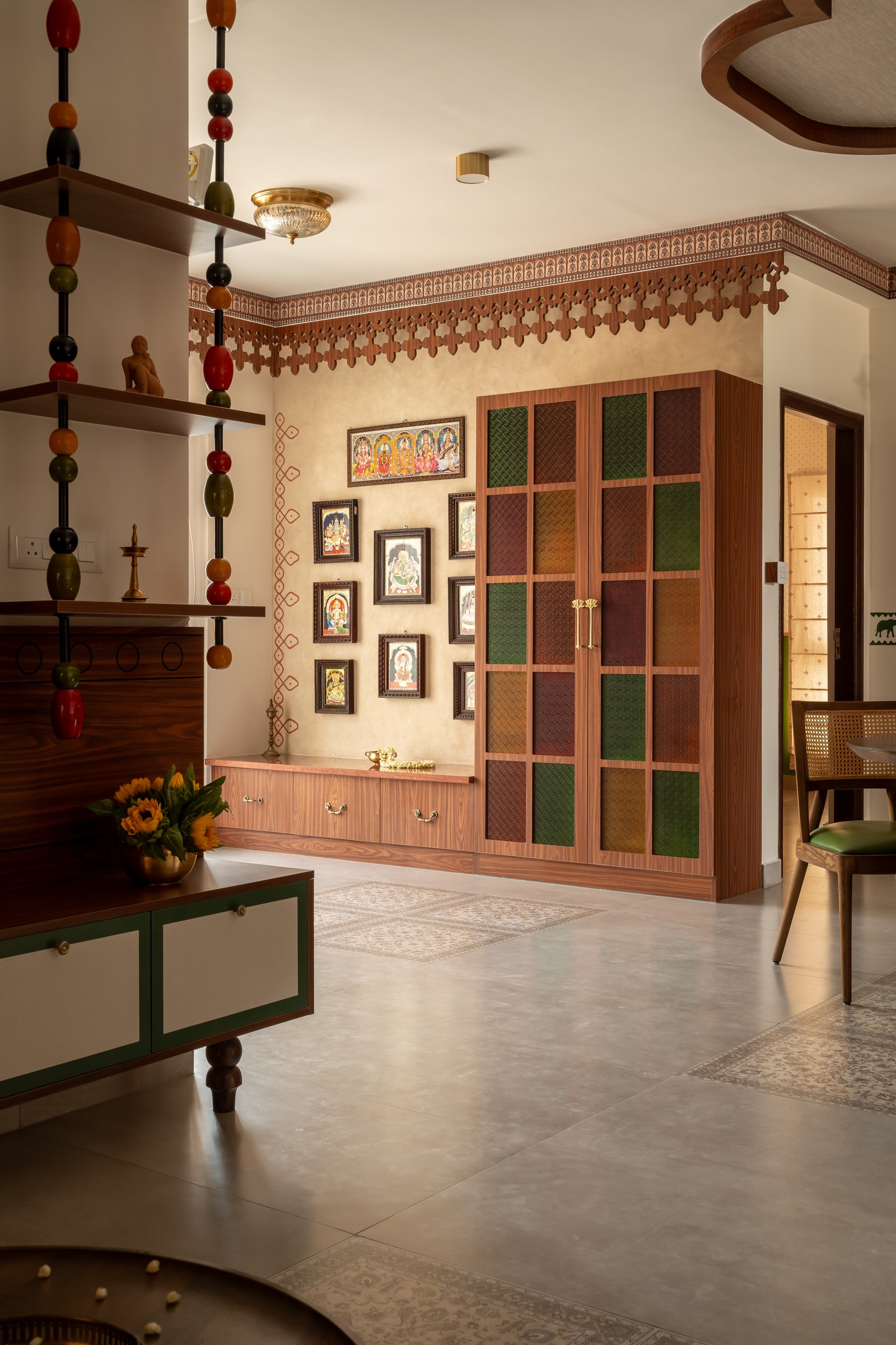 The pooja unit, framed by a carved wooden pelmet and a cabinet with coloured woven-fabric panels