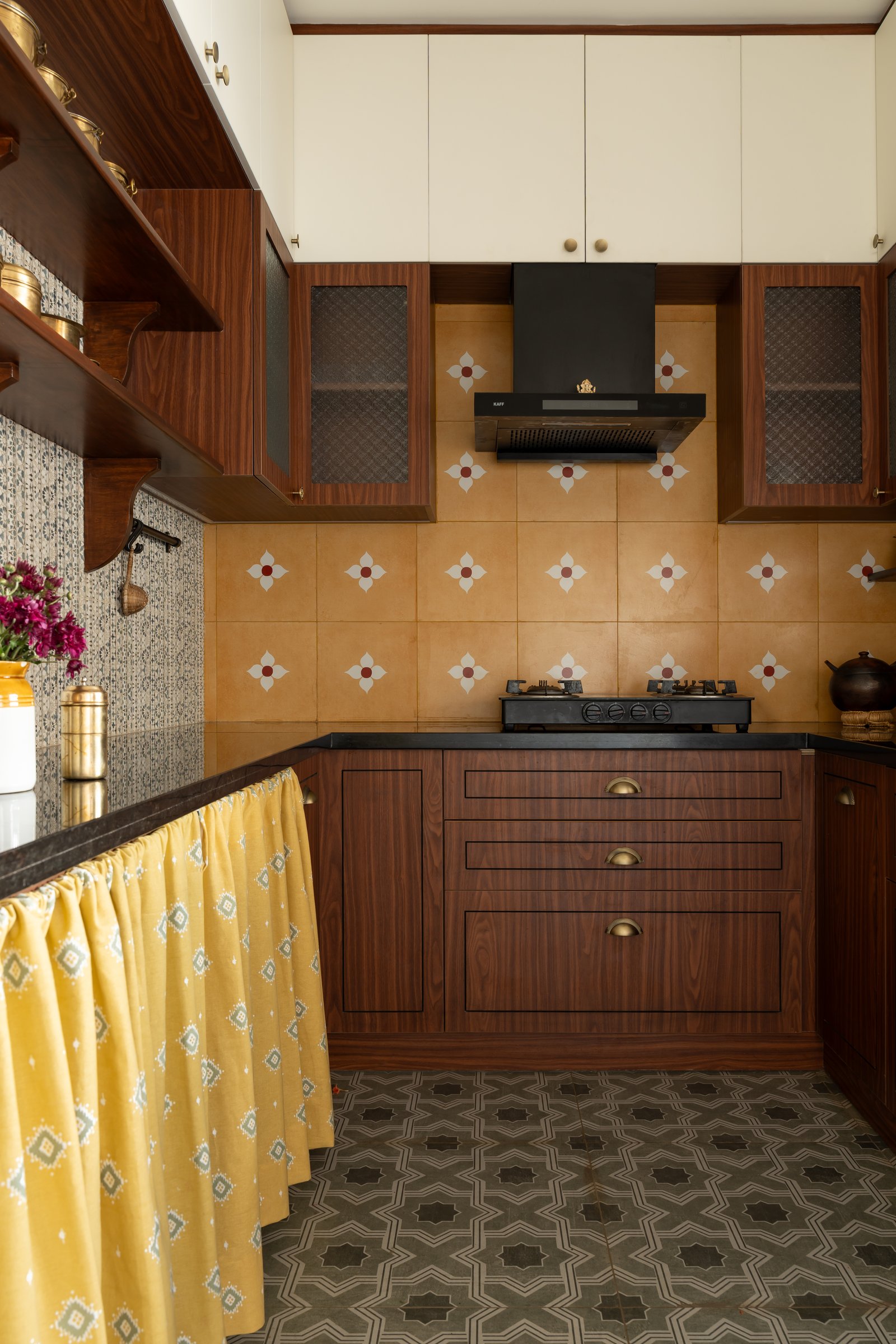 The kitchen, where a patterned ochre backsplash pairs with warm wooden cabinetry and a yellow fabric skirting along the island