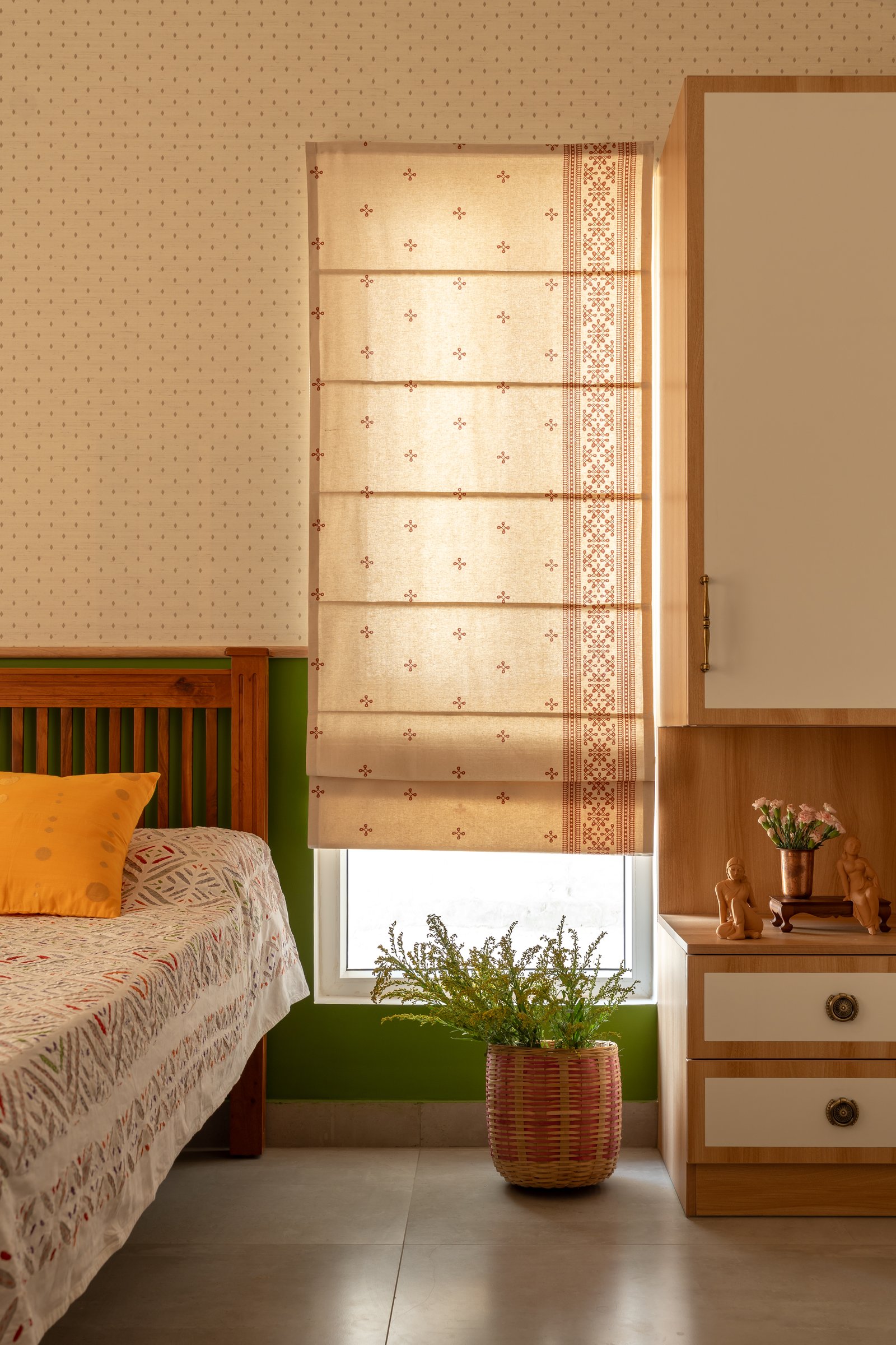 The guest bed against a mustard-green painted wall, its slatted wooden headboard echoing the living room's material language