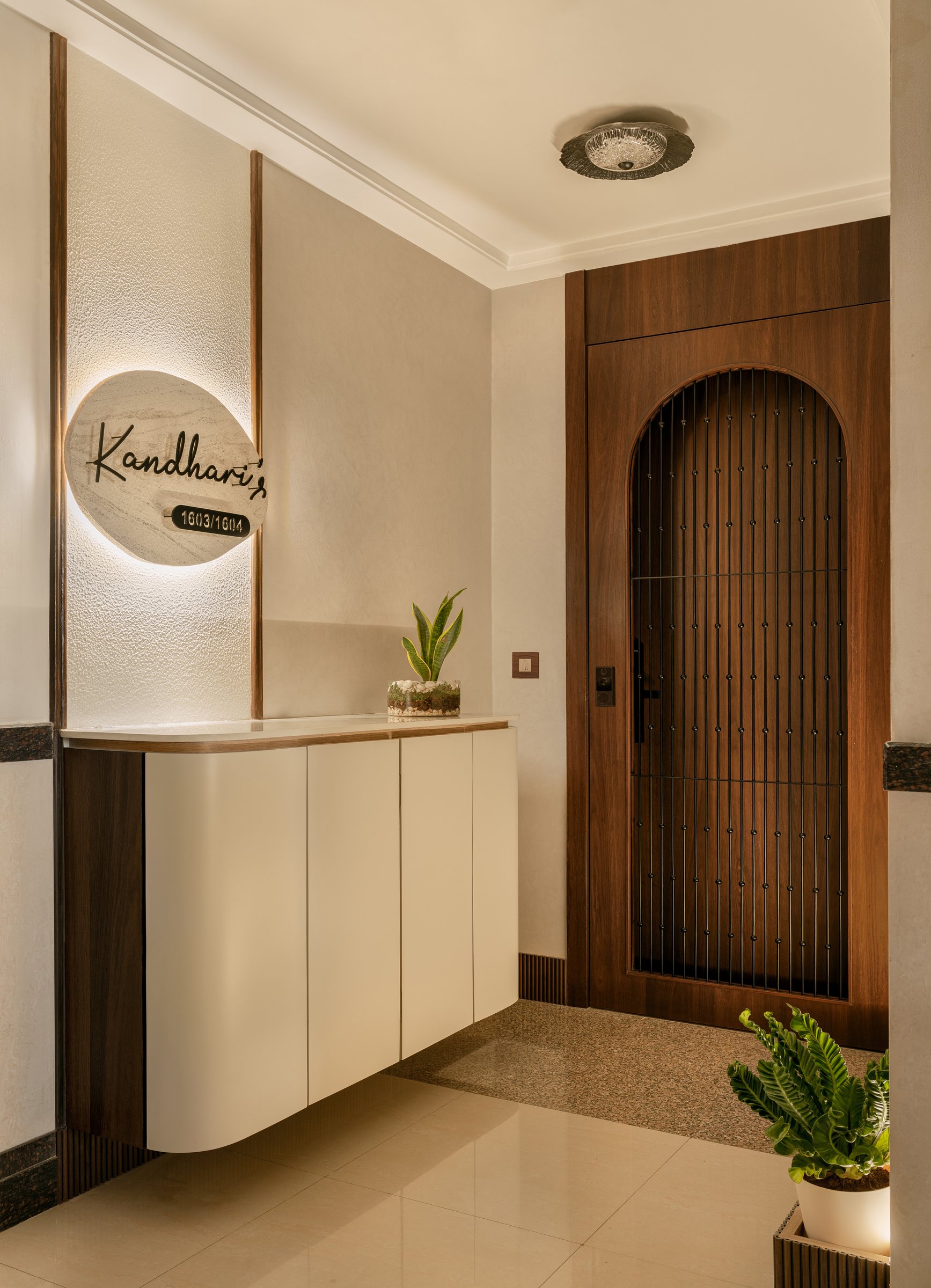 The entry, where a travertine nameplate and curved cream cabinet set a quiet, domestic welcome