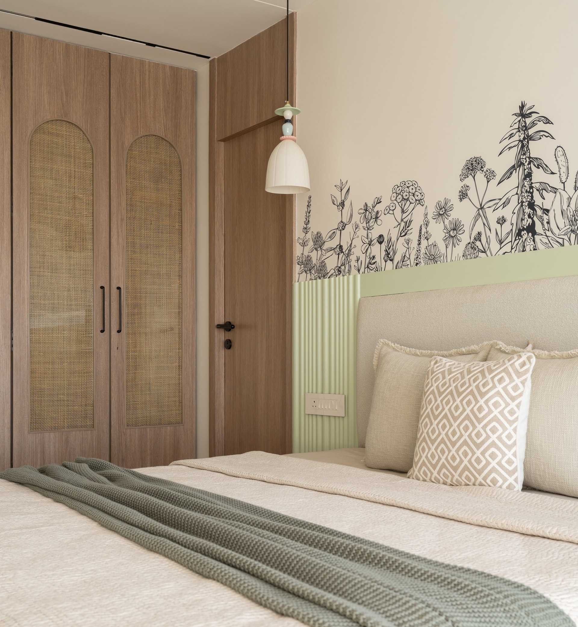 The arched cane-fronted wardrobe doors and a playful ceramic pendant beside the bed