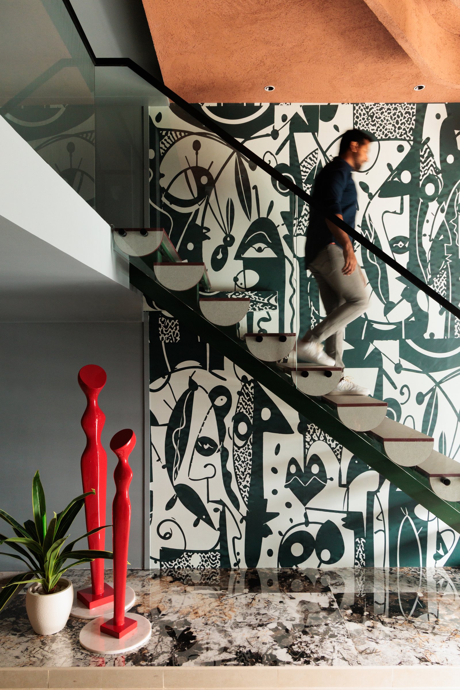 The floating stair, where mint-green stringers and veined marble meet the monochrome mural in a layered chromatic composition