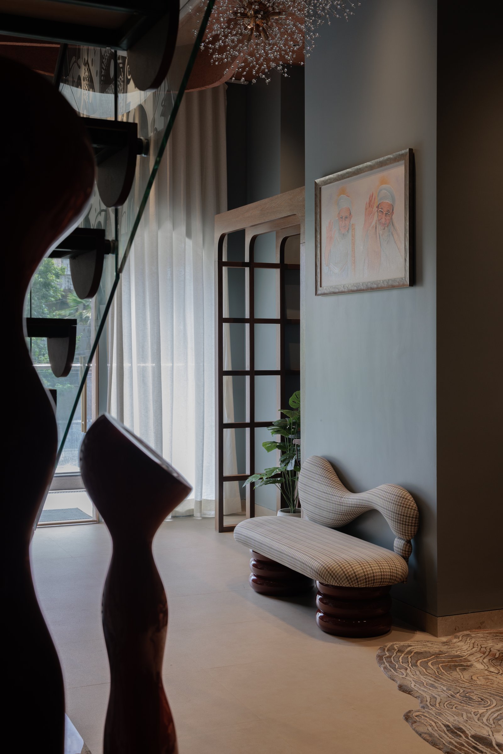 The entrance vignette, where a houndstooth-upholstered bench and a slender wooden grid screen set a quietly layered tone