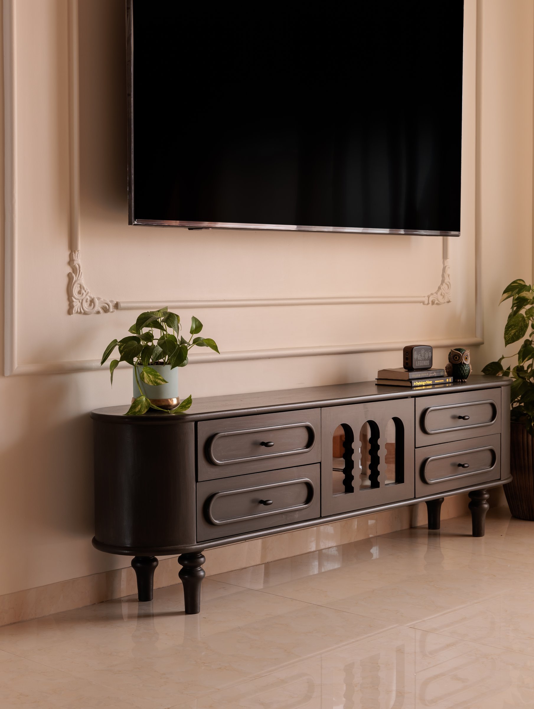 The curved media console, its arched centre detail softening the geometry of the wall-mounted screen above
