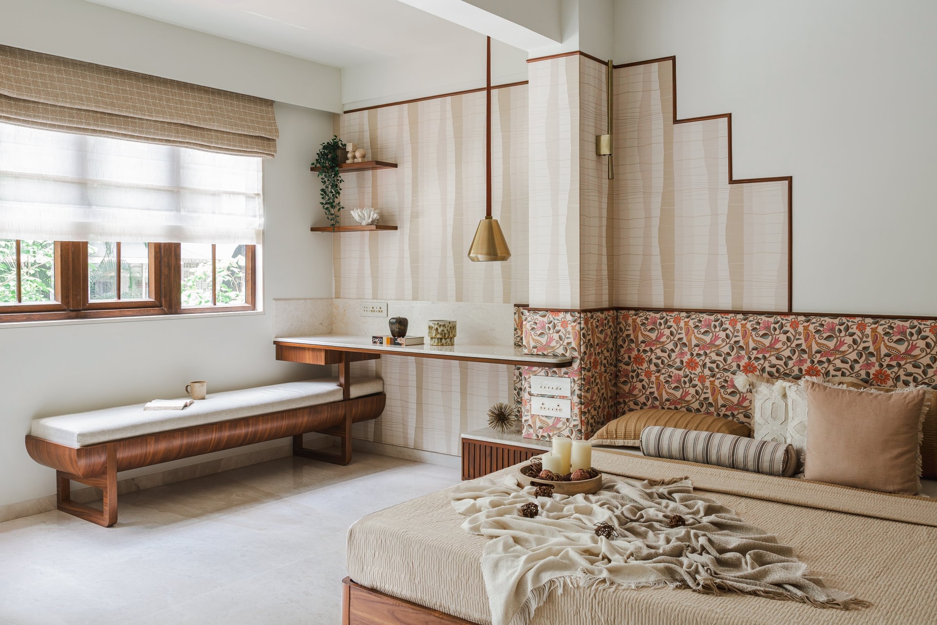 A curved wooden bench and slim stone-and-wood writing surface fold a work corner into the primary bedroom's composition