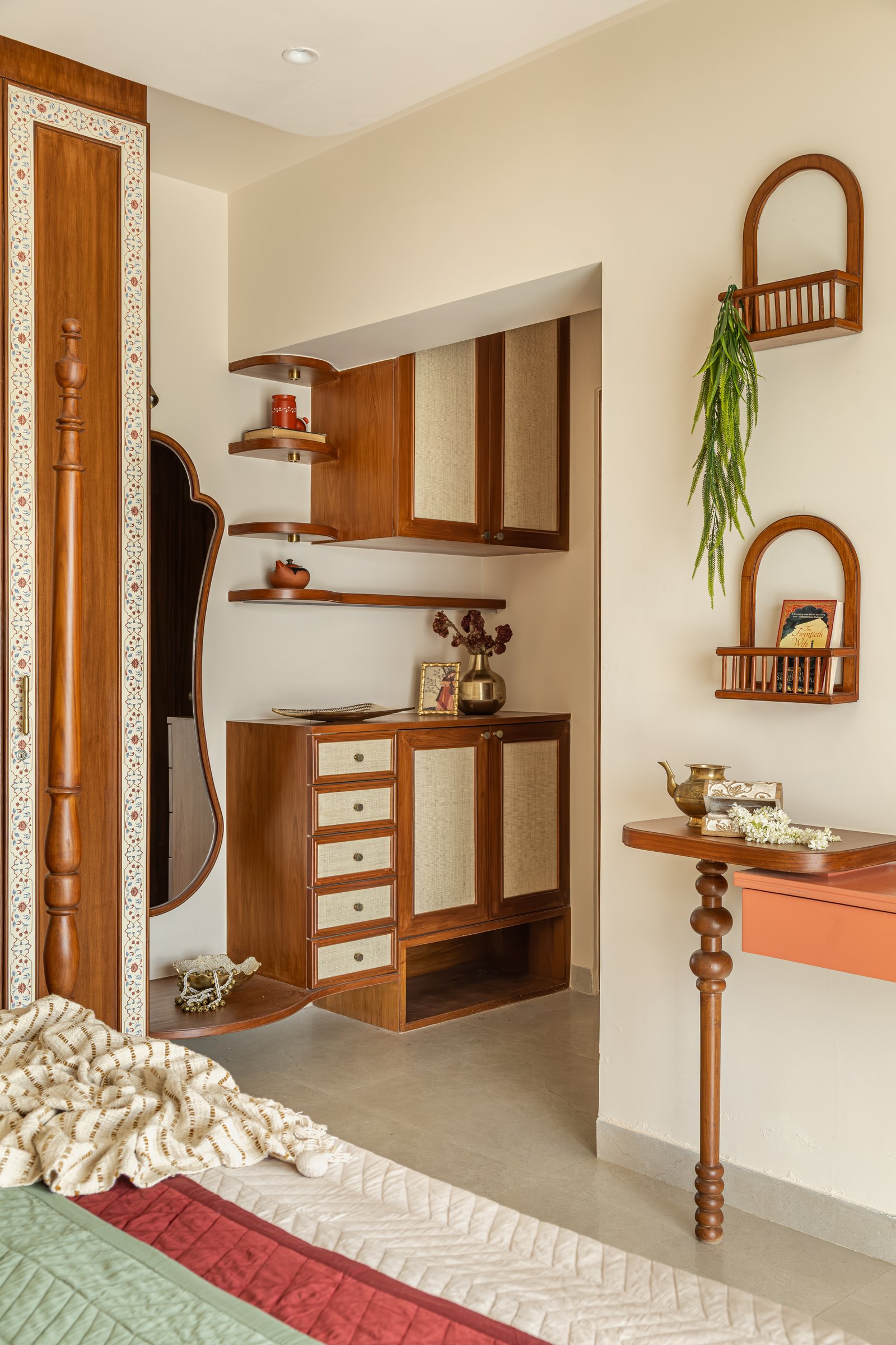The dressing nook within the primary bedroom, where a curvilinear mirror and cane-fronted joinery extend the room's material language