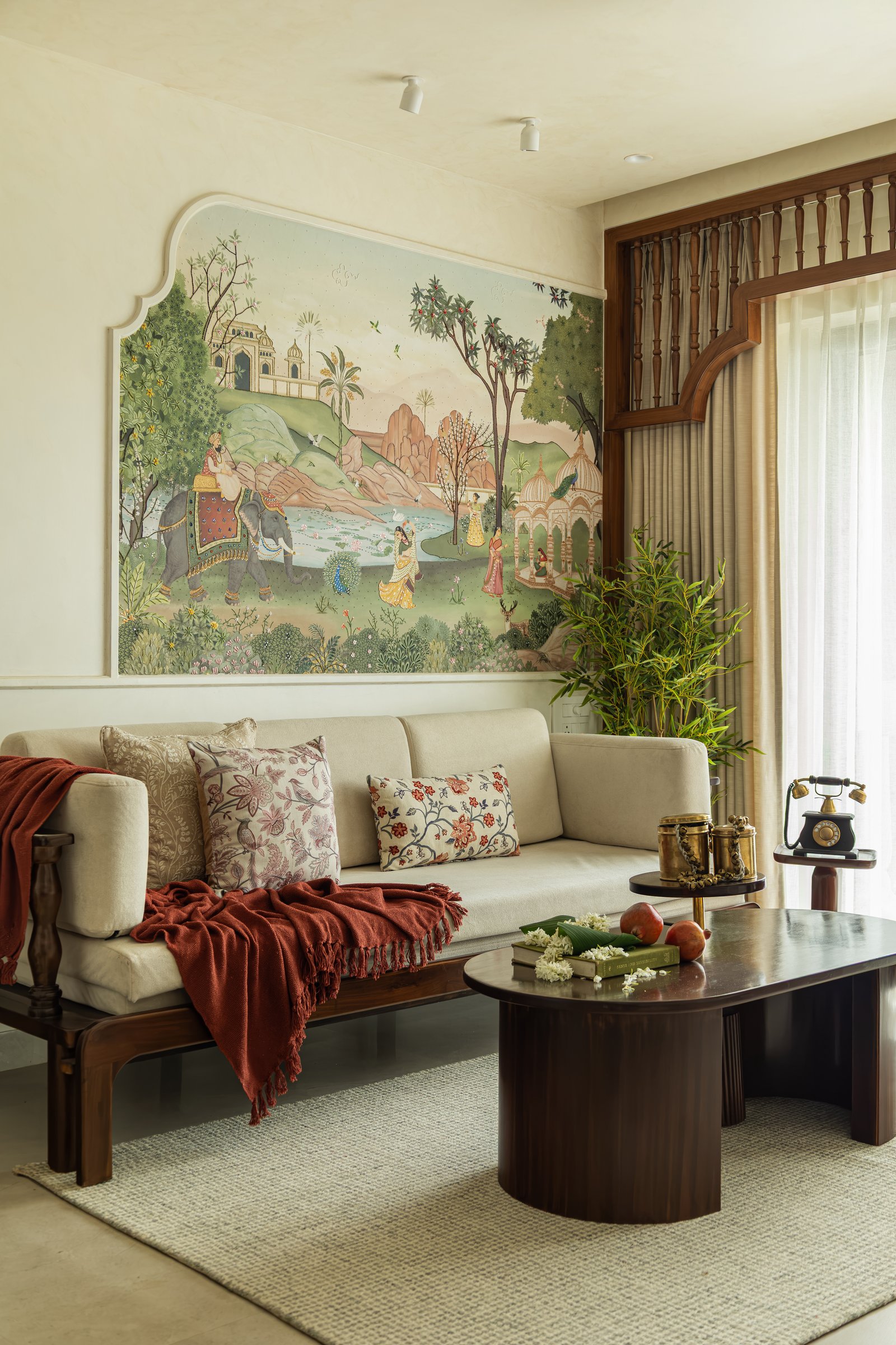 A closer view of the sofa and mural, where the dark wooden daybed-style frame and cream upholstery sit beneath the ivory-bordered painted scene