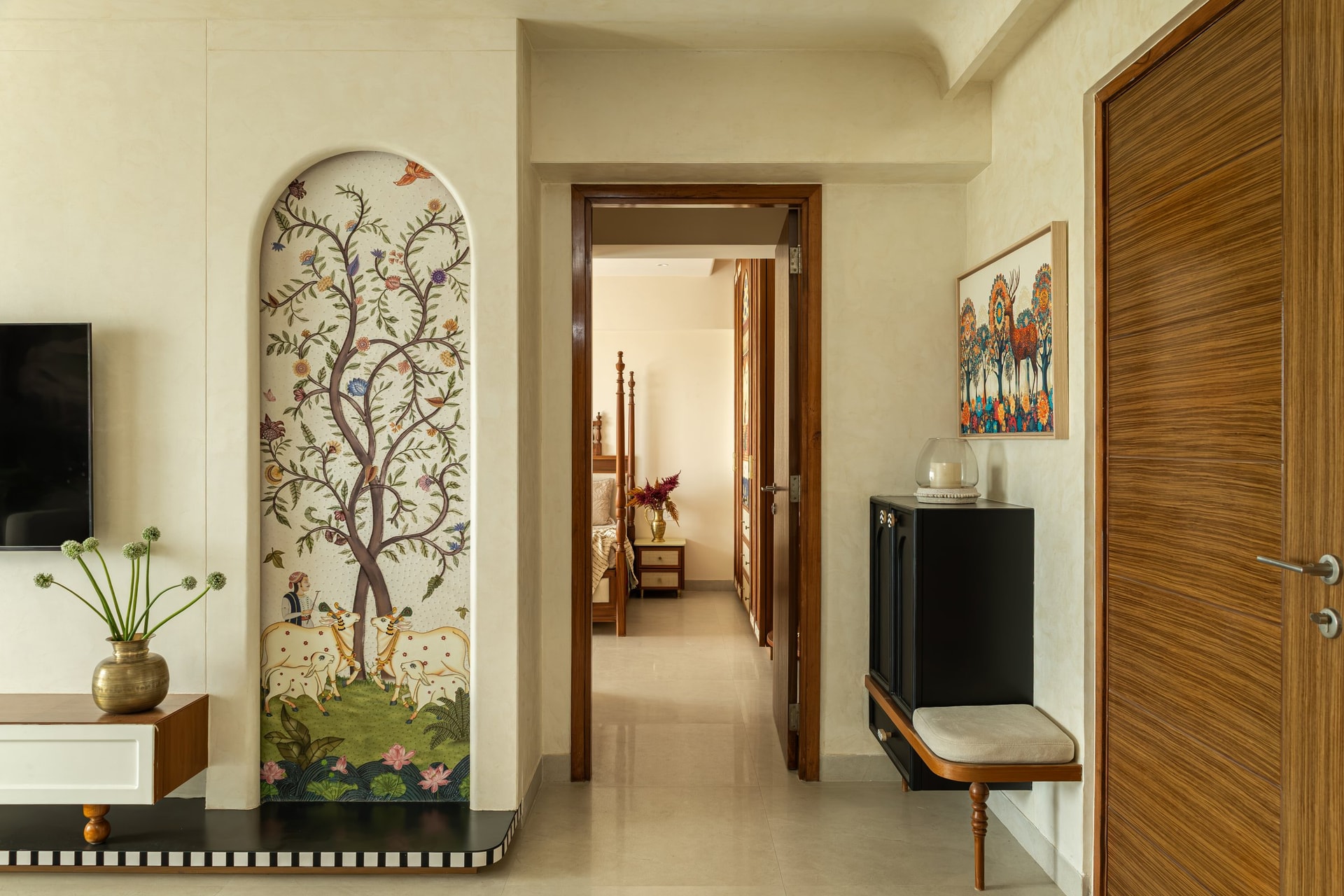 The entrance foyer, where a Pichwai-inspired arched panel and a black console with turned legs establish the home's layered material vocabulary