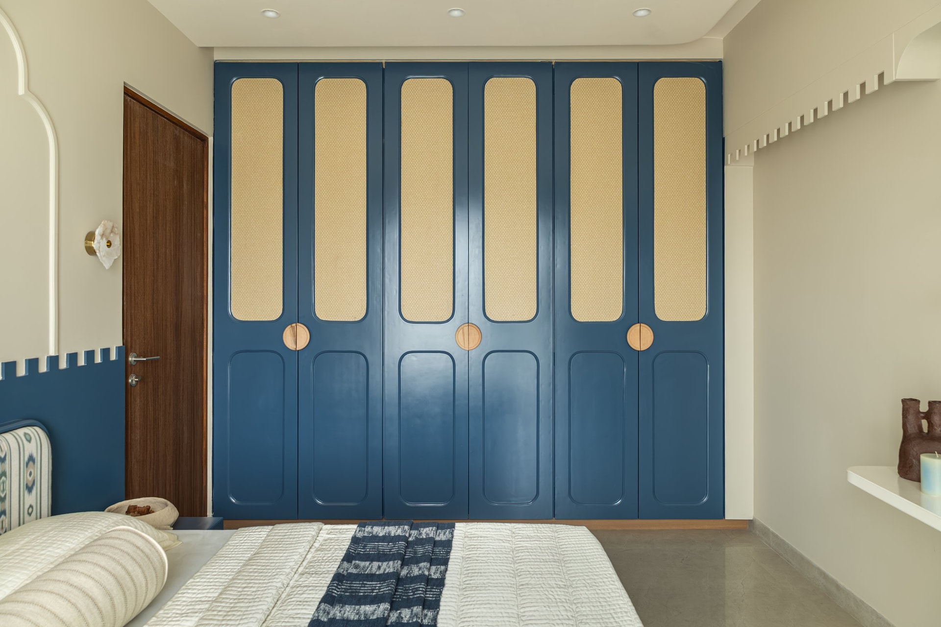 The wardrobe run in the second bedroom, where indigo panels with woven inserts carry the colour story across the room