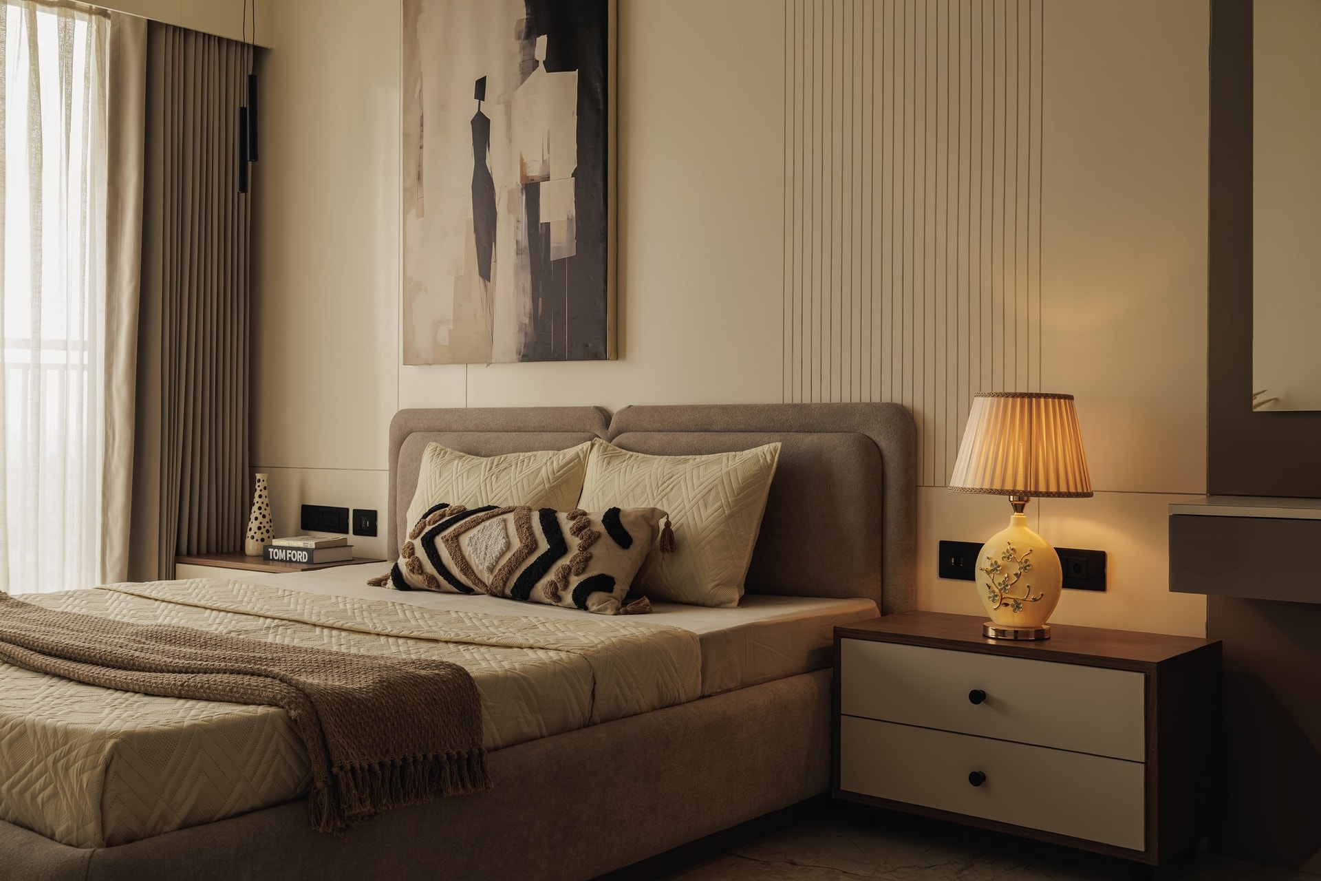 The second bedroom, with its upholstered bed set against ribbed cream panelling and a muted abstract painting above
