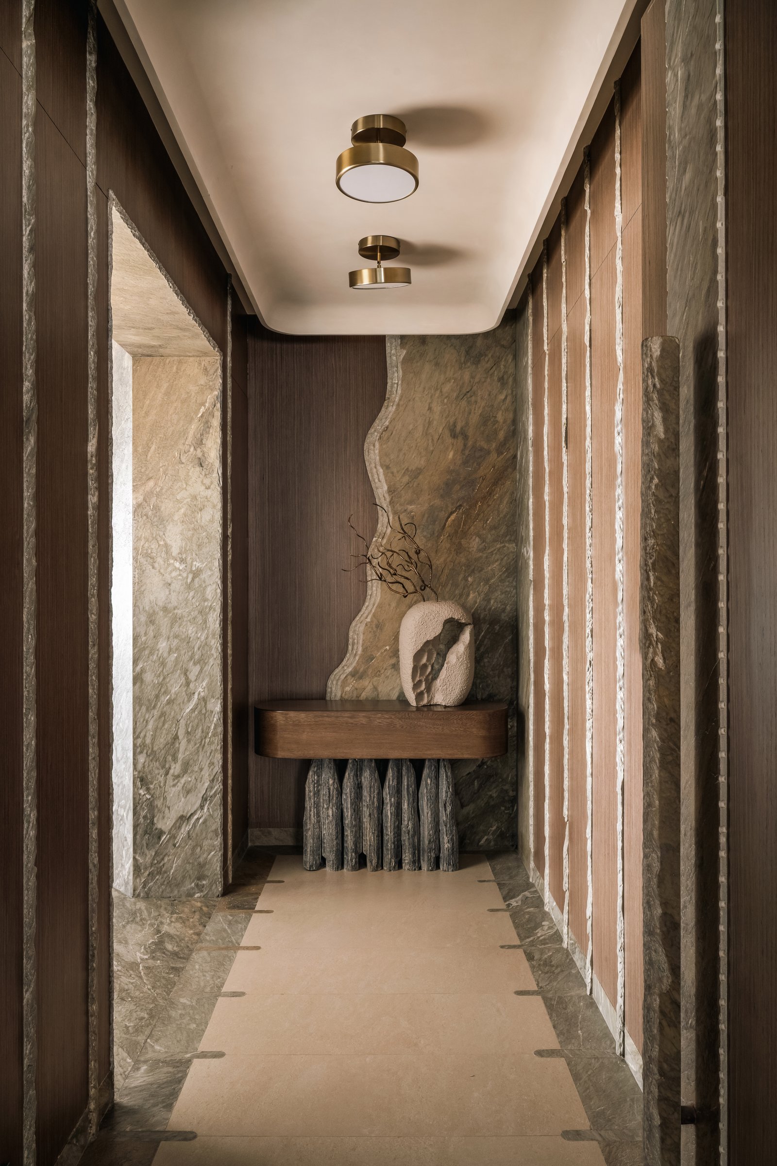 The foyer, where a hand-chipped marine-green marble slab backs a sculptural slate-and-veneer console