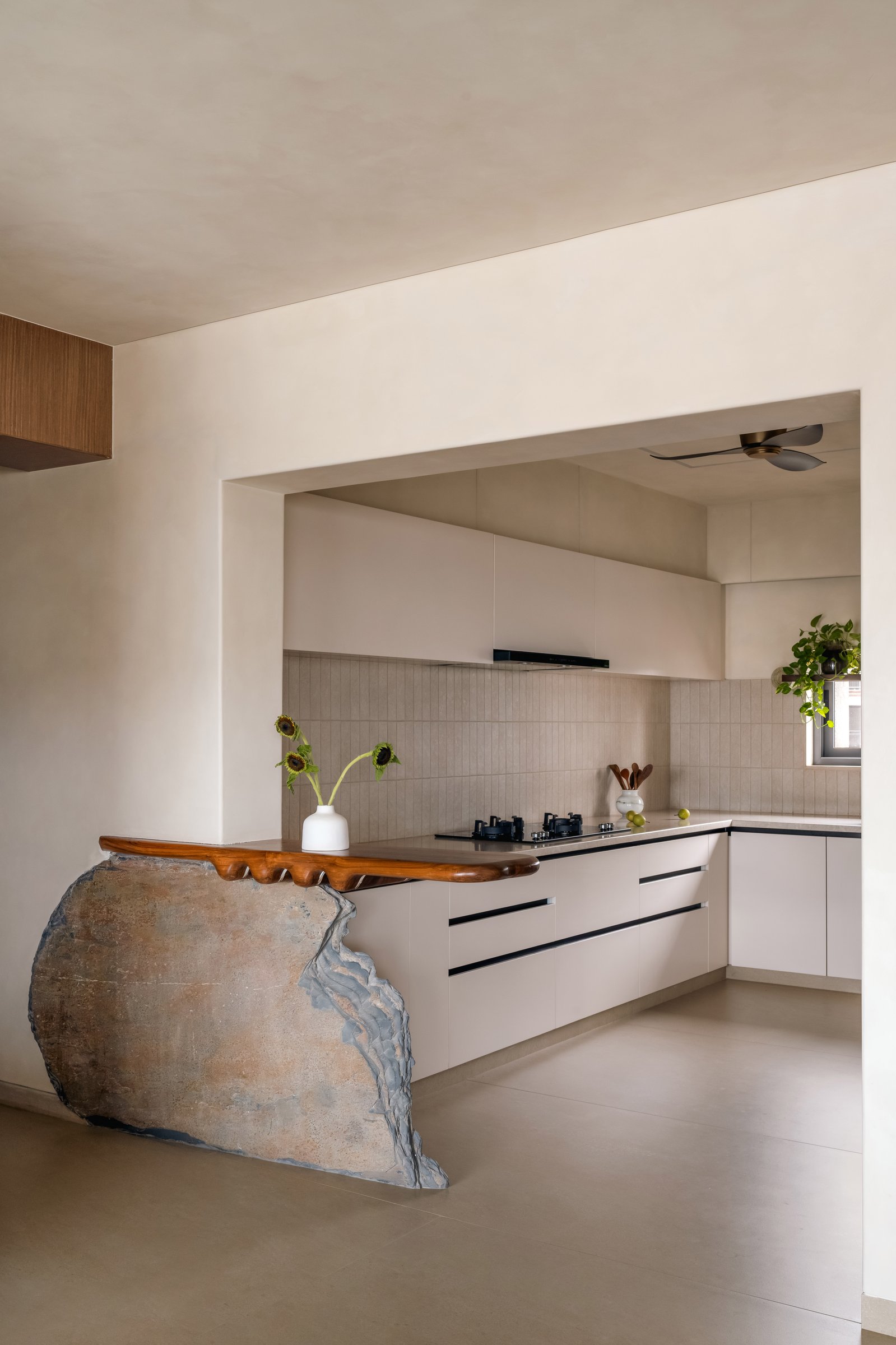 The kitchen, where pale cabinetry and a restrained backsplash give the sculptural breakfast counter room to speak