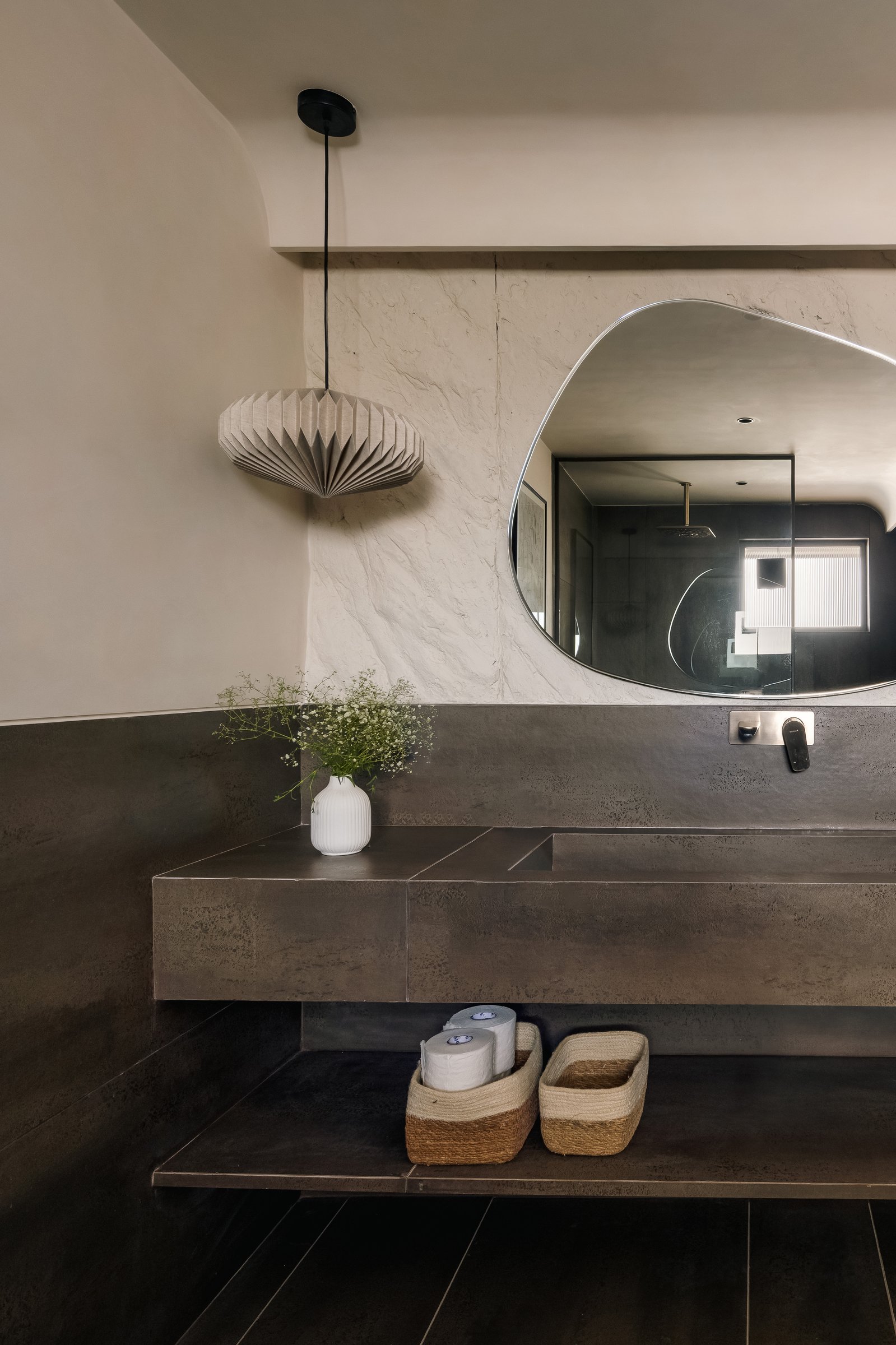 The powder bathroom, where a dark metallic vanity cantilevers from a rough-plastered wall
