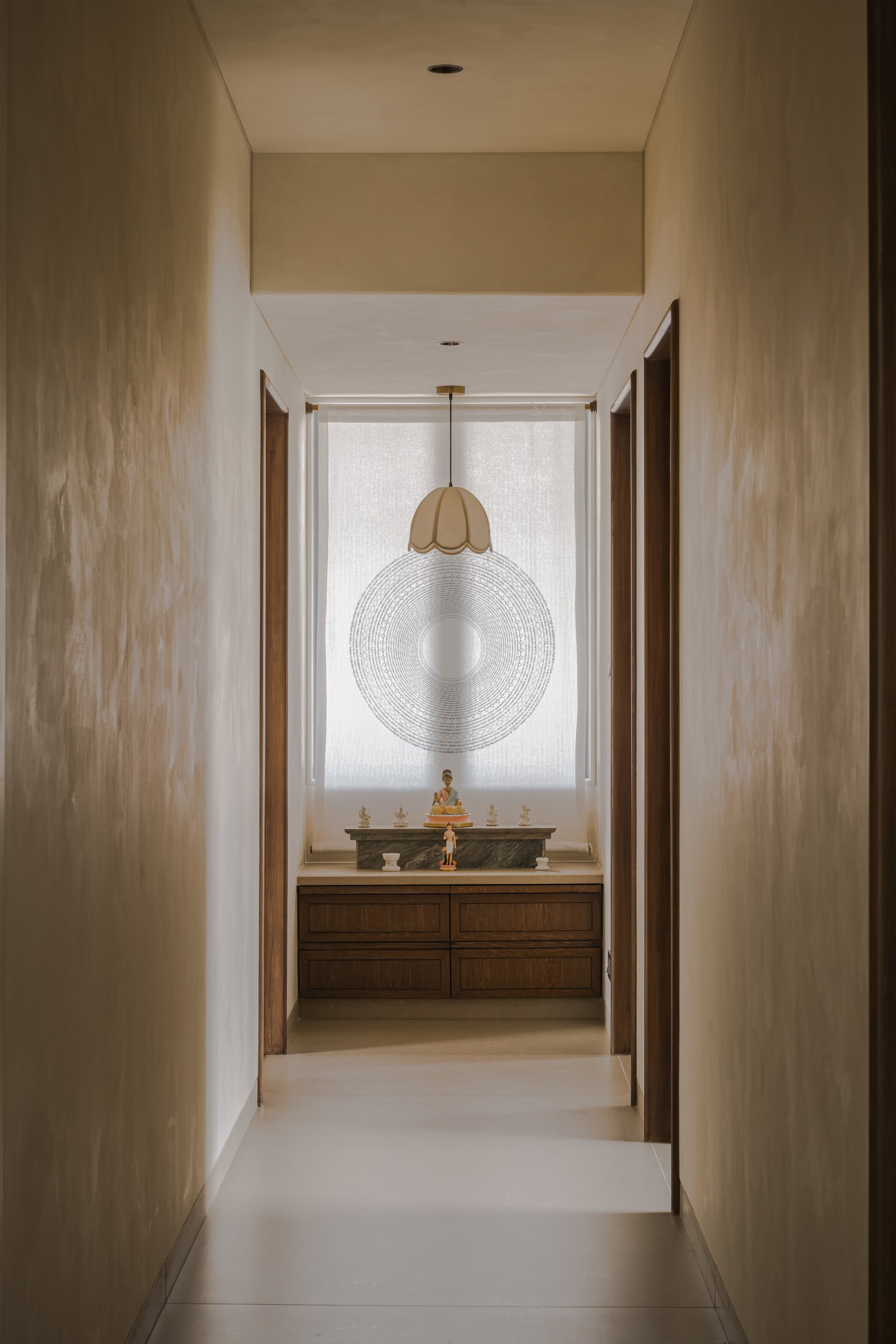The pooja space, framed by a sheer mantra-printed fabric and set on a green and white marble ledge