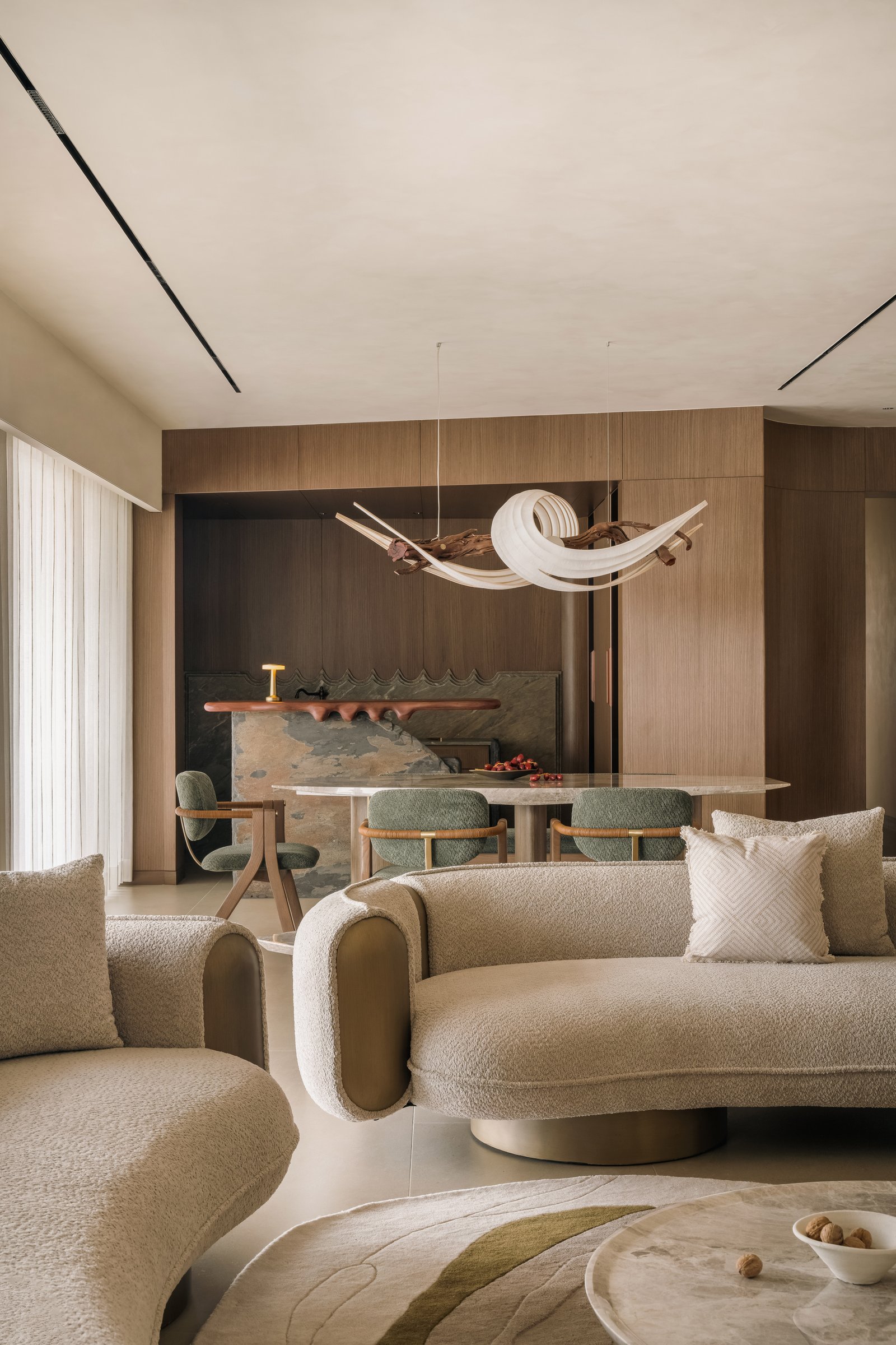 The dining and living areas as a single integrated core, with Radhika Sanghavi Studio's sculptural light installation above the dining table