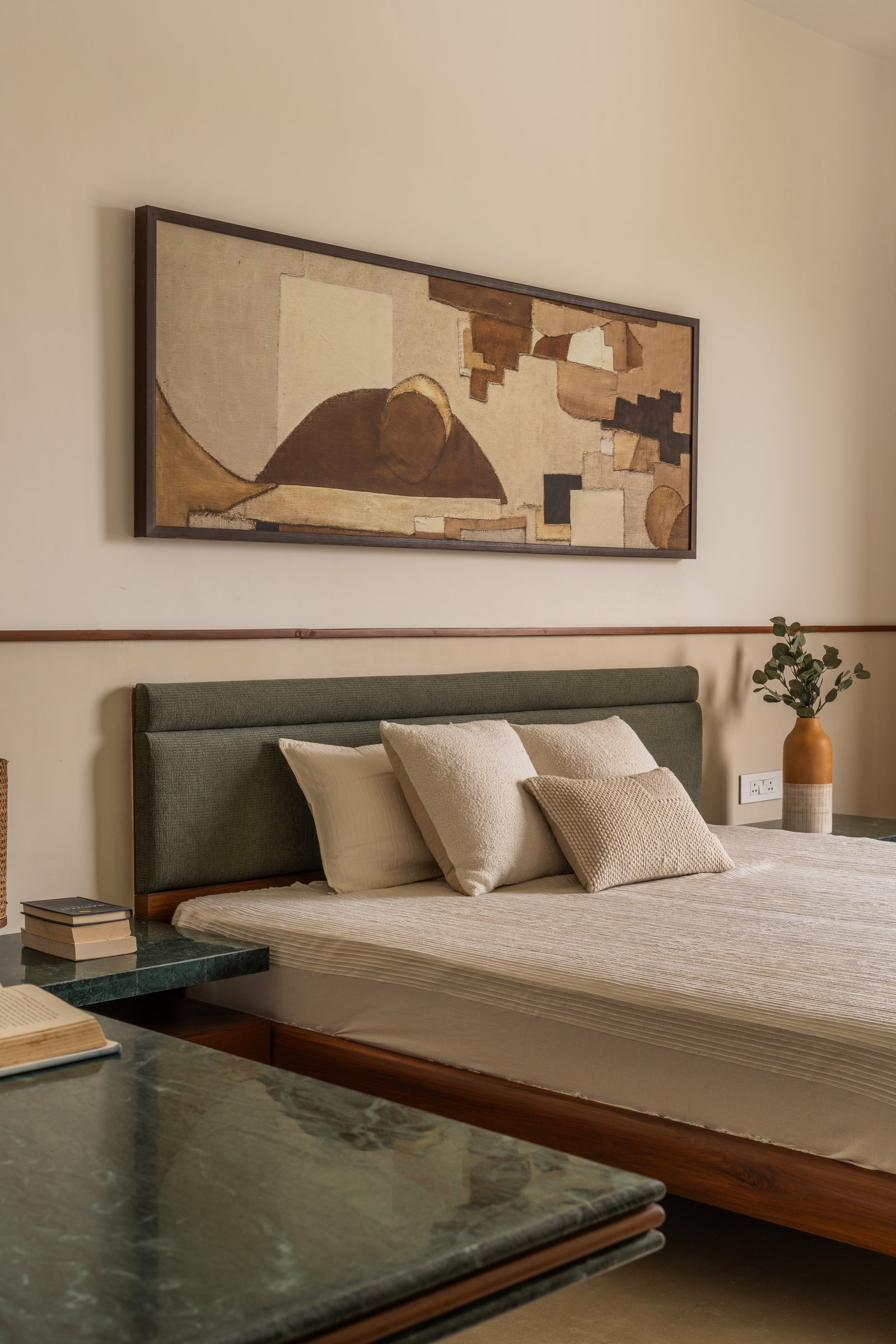 The second bedroom, where a sage headboard and a long horizontal artwork reframe the palette through a cooler lens