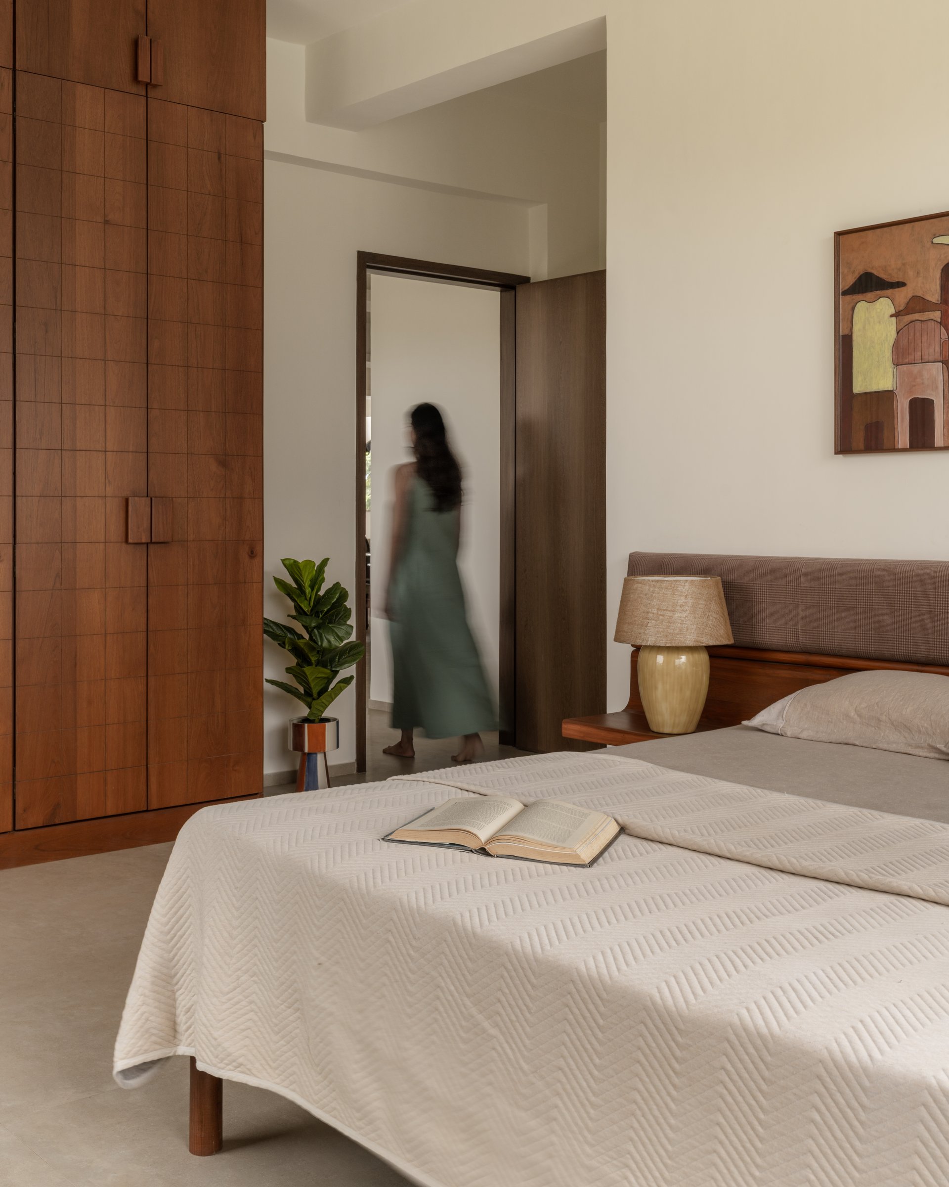 The wardrobe wall holds the room with quiet weight while the doorway opens back toward the living areas