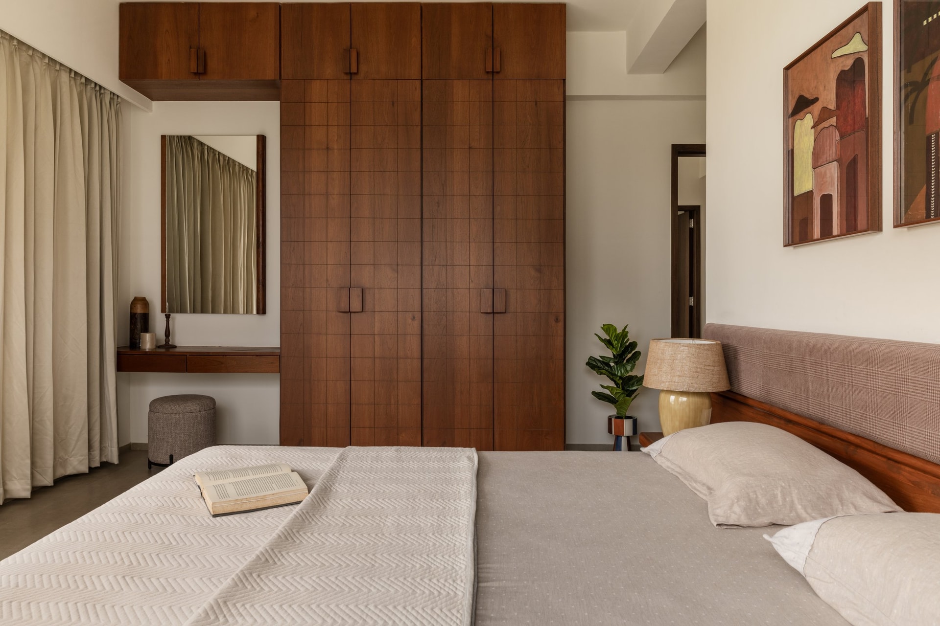 The primary bedroom, organised around a tall wall of gridded wooden wardrobes with a dressing recess alongside
