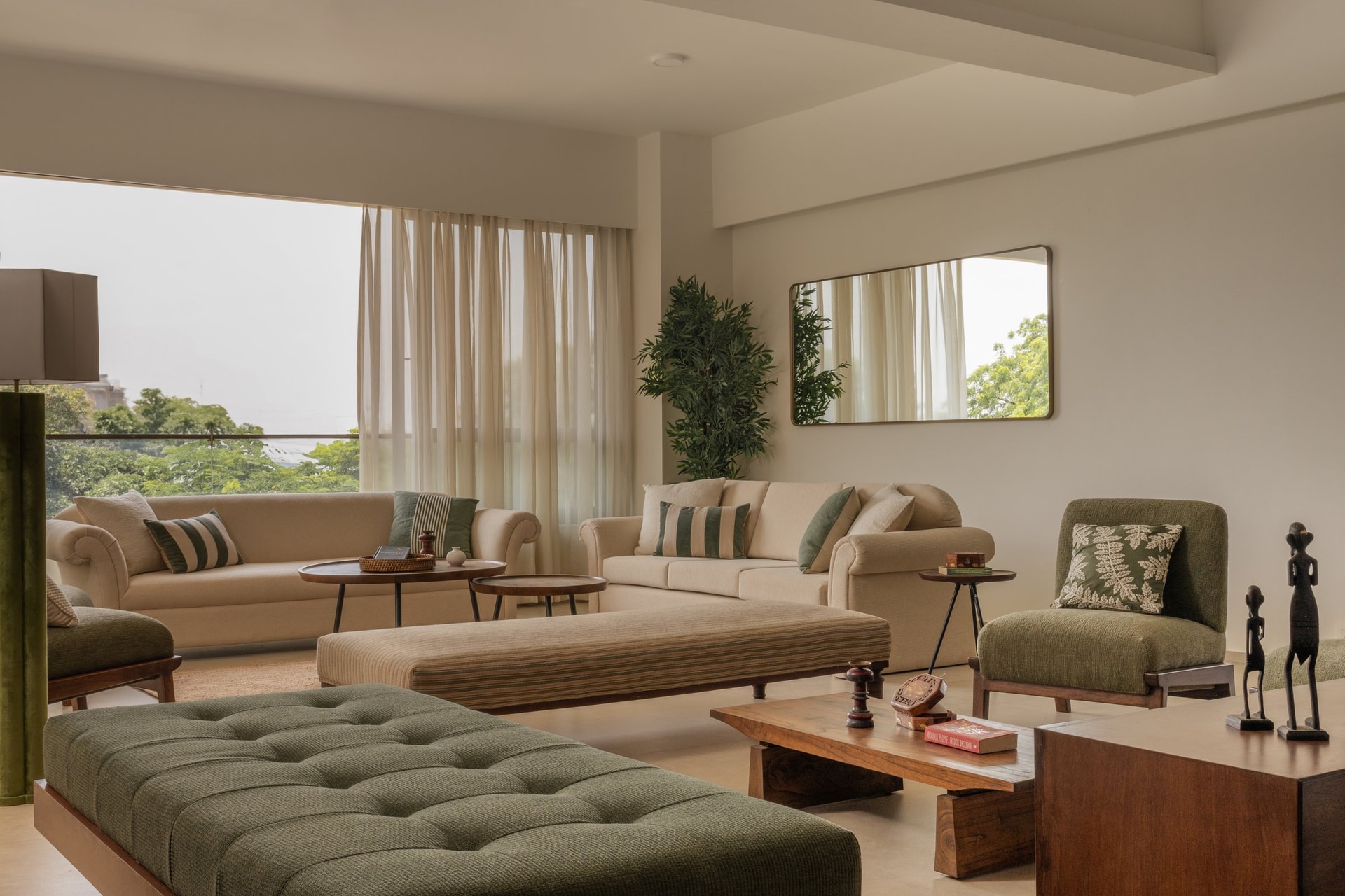 A second view of the living room, where an olive chair and tufted ottoman deepen the palette's green register