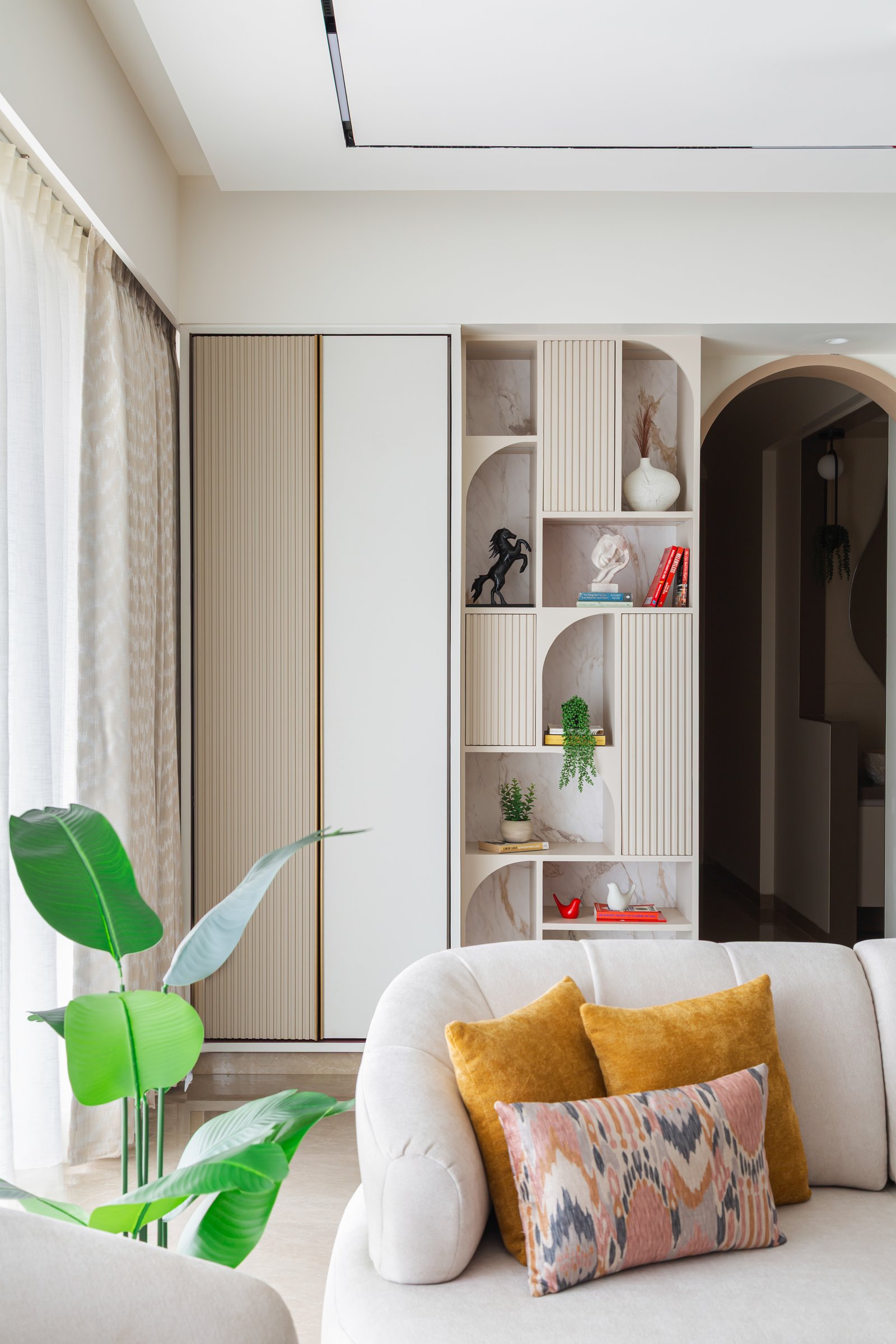 The arched shelving unit beside the sofa, with ribbed panels and open niches set against veined stone