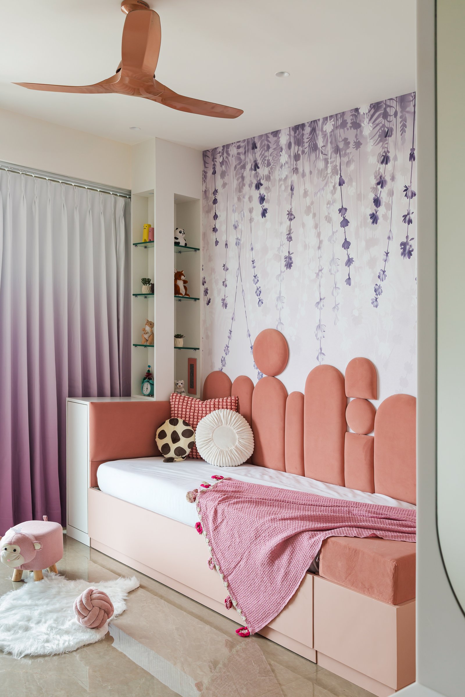 The daughter's room, where a sculptural pastel-pink headboard sits against a botanical wallpaper