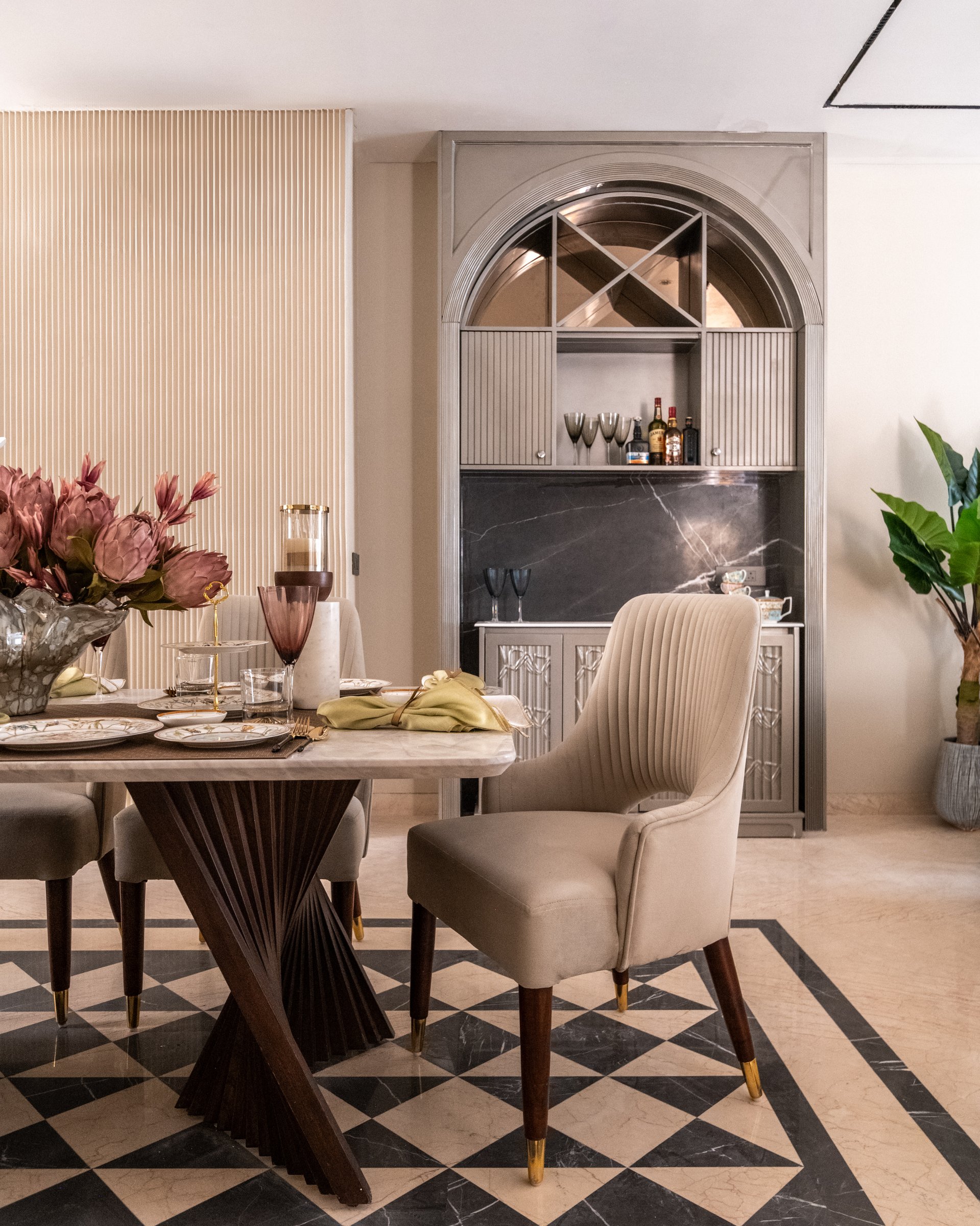The dining area, defined by a sculptural sliced-wood table base and a chequered marble floor inlay