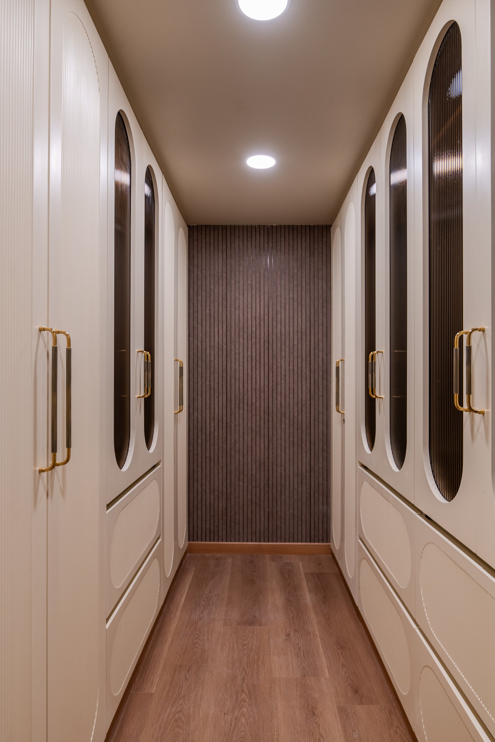 The walk-in wardrobe between master and bath, its arched fluted-glass fronts creating a disciplined architectural passage