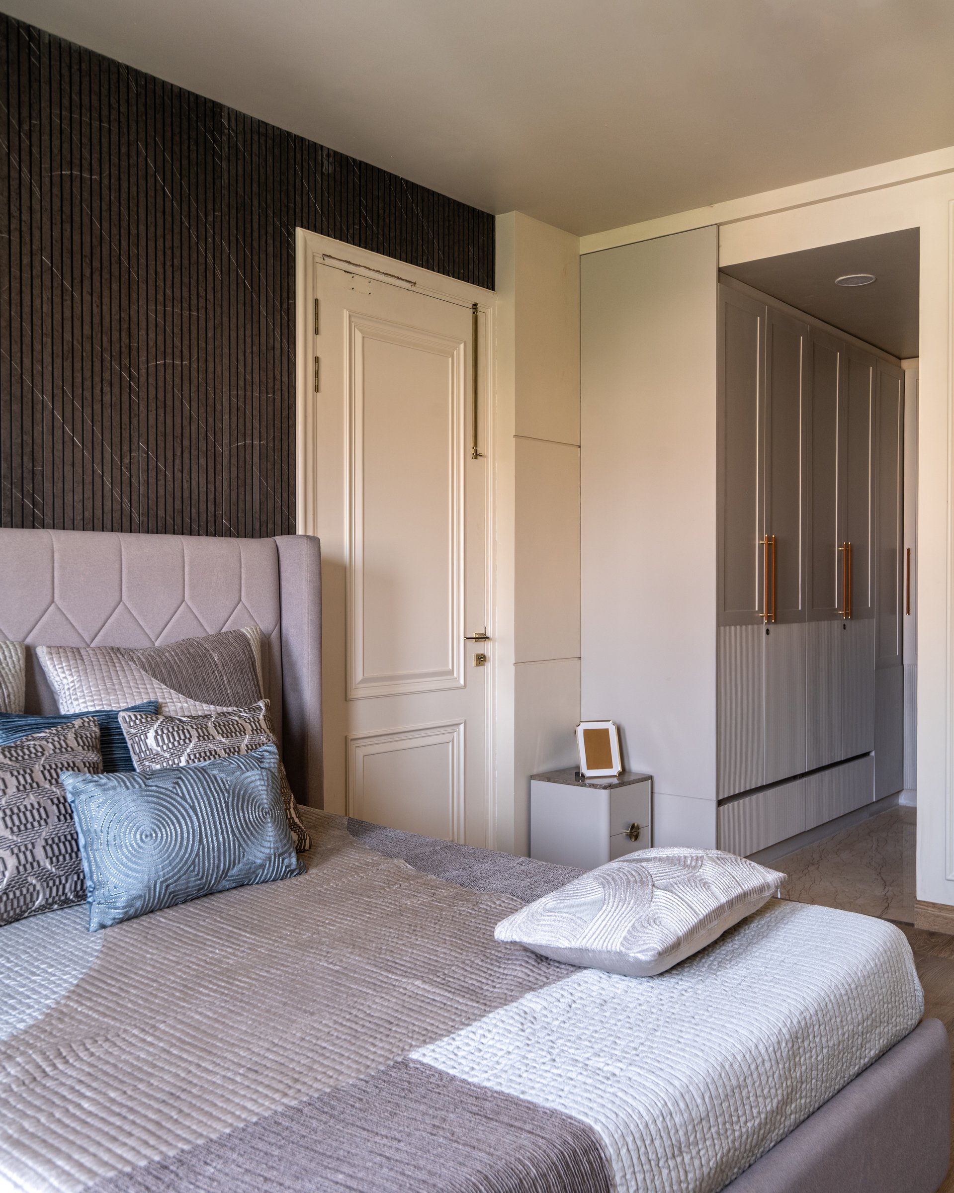 The adjacent zone of the same suite, where panelled wardrobes with brass pulls extend the architectural logic